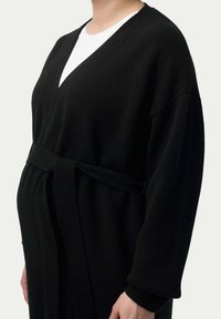 Svart, lätt cardigan med V-ringning, vida ärmar och knytband i midjan. Mjuk textur och avslappnad passform, lämplig för lager på lager.