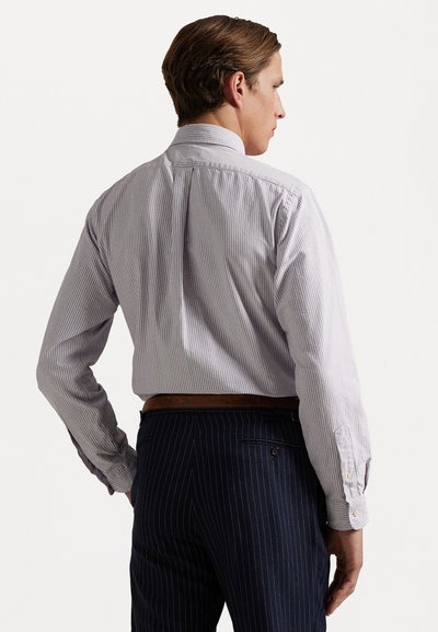 Chemise légère à rayures avec un col italien, des poignets à boutons et une coupe ajustée, associée à un pantalon à fines rayures foncées et une ceinture marron.