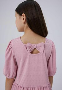Rosa Kleid mit kurzen Puffärmeln, strukturiertem Stoff und einem Rückenschlüsselloch-Detail, geschmückt mit einer Schleife. Weiches, leichtes Material.
