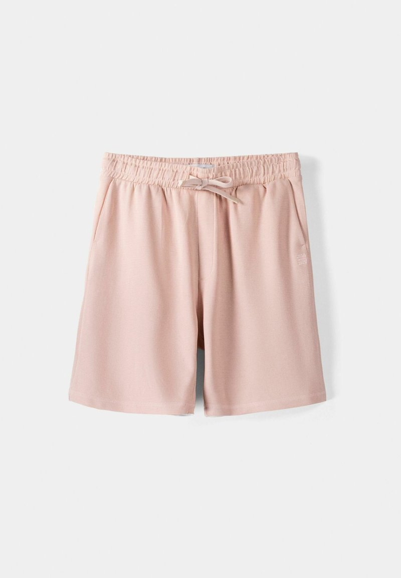 Shorts décontractés rose clair avec taille élastique, cordon de serrage frontal et poches latérales, présentés sur un fond blanc uni.