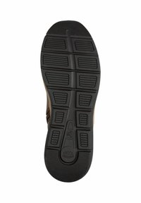La semelle de la chaussure présente une base en caoutchouc noir avec des rainures profondes pour l'adhérence, accompagnée d'un intermédiaire texturé couleur tan et d'un détail d'amortisseur.