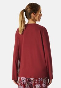 Langermige, wijnrode top met een relaxed fit, voorzien van een ronde hals en een soepele textuur, gecombineerd met gepatternde broek.
