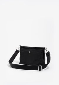 Borsa a tracolla nera realizzata in tessuto con una texture sottile. Presenta una forma rettangolare, una tracolla regolabile e una chiusura a scatto metallica circolare.