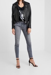 Svart läderbikerjacka med silverdetaljer, åtsittande svart linne med paljetter, grå skinny jeans och svarta klackar med remmar.