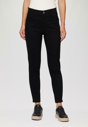 Zwarte skinny broek van gladde katoen met een knoopsluiting en steekzakken, gecombineerd met zwarte sneakers met een gestructureerde zool.