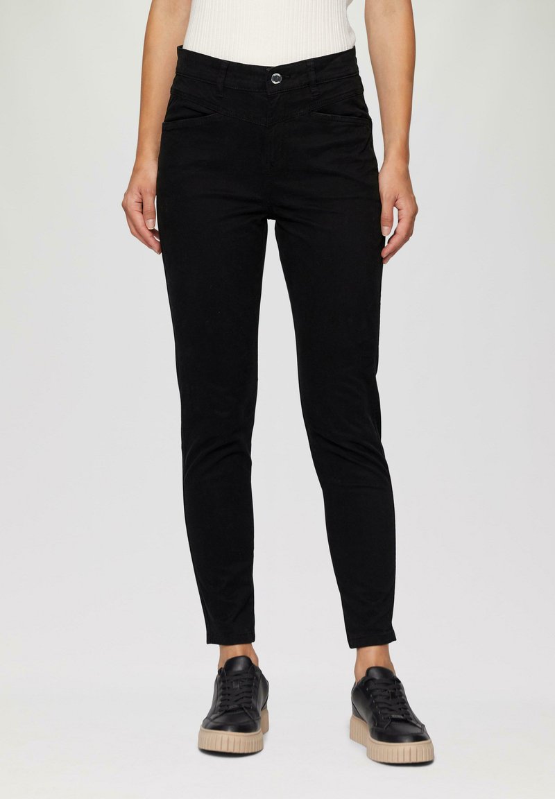 Zwarte skinny broek van gladde katoen met een knoopsluiting en steekzakken, gecombineerd met zwarte sneakers met een gestructureerde zool.