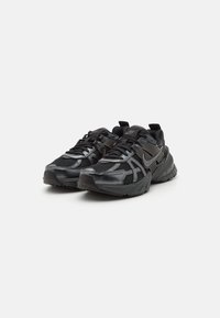 Sneaker sportive nere con upper in mesh e sintetico, suola spessa e imbottita, e un sistema di allacciatura prominente. Presenta il logo Nike sui lati.