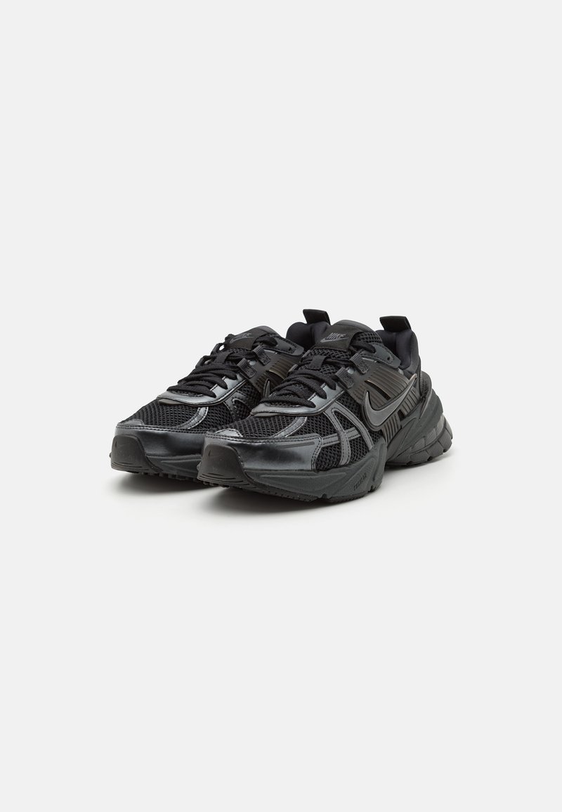 Baskets de sport noires avec tige en mesh et synthétique, semelle épaisse et rembourrée, et système de laçage bien visible. Présente le logo Nike sur les côtés.