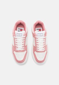 Rosa och vita sneakers med övre av duk, snörning, perforerad tå och gummisula. Har en märkestämpel på tungan.