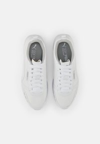 White athletic shoes with textured synthetic material, rounded toe, lace-up design, and grey insoles featuring "SOFTFOAM" branding.
