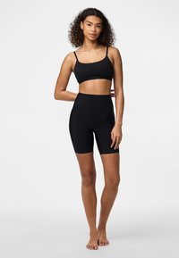 Svart crop top och hög midjebyxa i mjukt, elastiskt tyg. Lättviktig och figurnära design med tunna remmar.