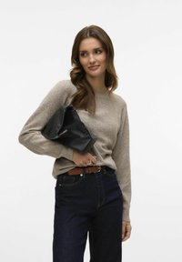 Beige knitted sweater with long sleeves, paired with dark blue jeans. Holding a black leather clutch bag. Brown belt with a simple buckle.