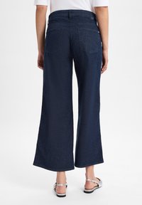 Wijdvallende denim broek in donkerblauw, met een hoge taille, twee achterzakken en een gladde textuur. Accentuated met stikseldetails.