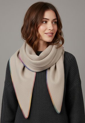Woman with shoulder-length brown hair wearing a beige triangular scarf with multicolor stitched edges over a dark gray knit sweater.