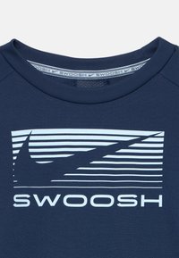 Tamsiai mėlynas marškinėlių apykaklė su baltomis horizontaliomis juostelėmis ir swoosh logotipu virš žodžio "SWOOSH" ryškiomis baltomis raidėmis.