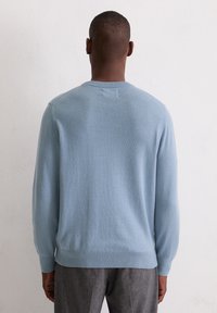 Jasnoniebieski sweter z dzianiny z prążkowanym dekoltem i mankietami, o gładkiej fakturze i luźnym kroju, pokazany od tyłu.