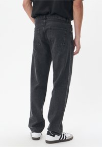 Jeans de mezclilla gris oscuro con un corte relajado, que presentan una cintura alta, diseño de cinco bolsillos y detalles visibles de costura.