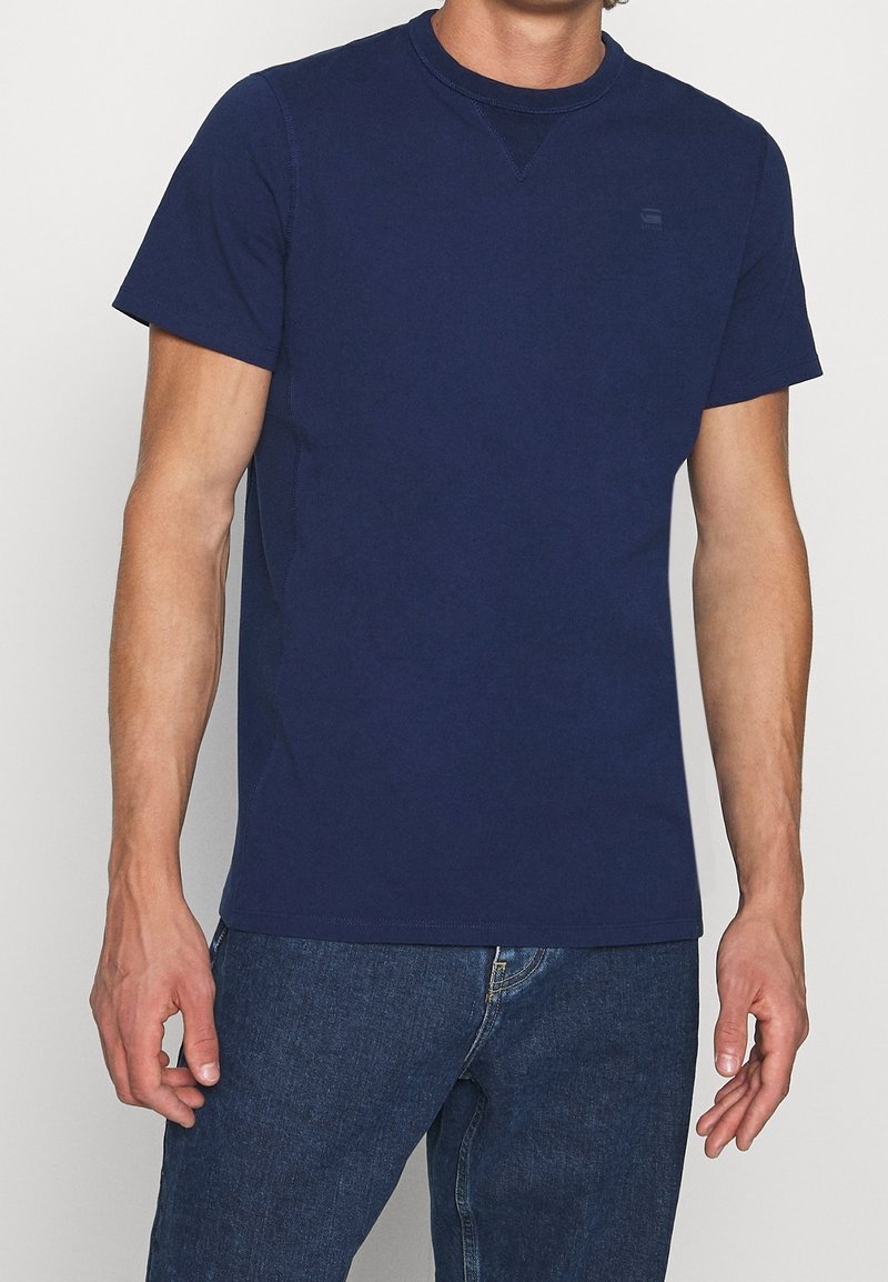 Camiseta de manga corta azul marino confeccionada en algodón, con un escote redondo y un pequeño logo en el pecho, de diseño ajustado y textura suave.