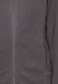 Giacca in pile grigio scuro con zip completa, superficie texturizzata e tessuto morbido. Caratterizzata da una vestibilità aderente e senza hardware o dettagli visibili.