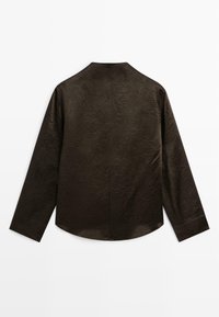 Camicia a maniche lunghe di colore marrone scuro con una finitura texturizzata, colletto alto e taglio dritto. Presenta un design minimalista e nessun bottone visibile.