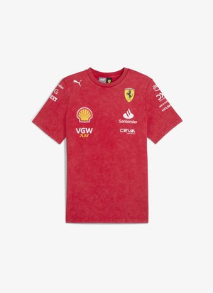 Czerwona bawełniana koszulka z okrągłym dekoltem, z logo Ferrari oraz różnymi nadrukami sponsorów na przodzie i rękawach. Miękka, teksturowana faktura.