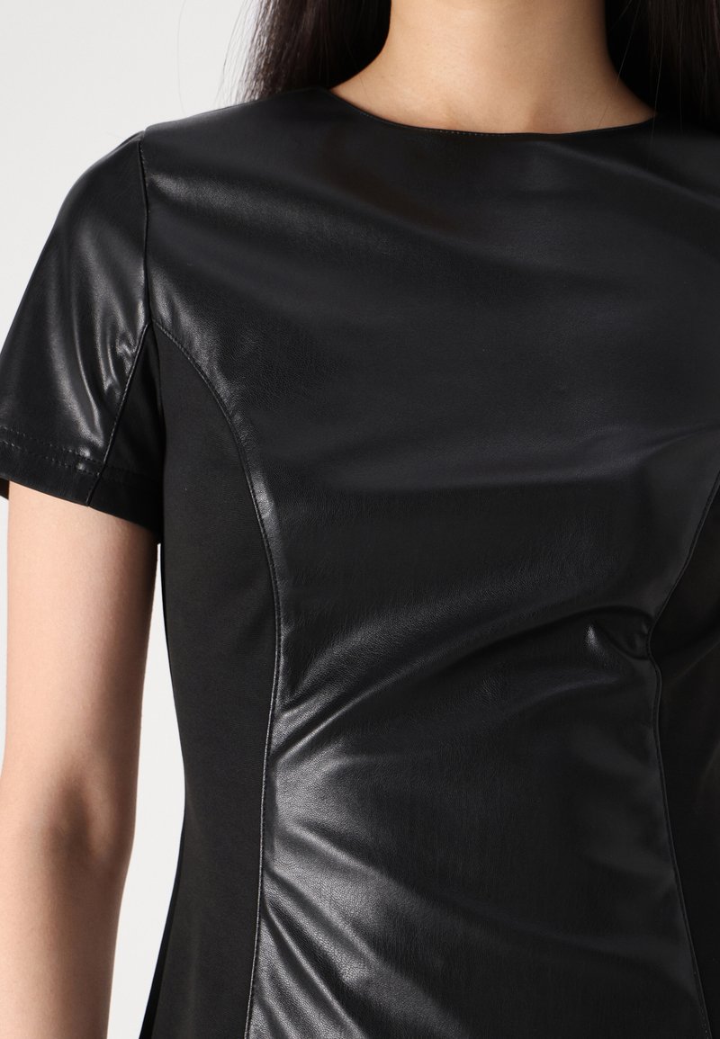 Schwarzes Kurzarmoberteil mit einer glatten Lederoberfläche auf der einen Seite und einem matten Stoff auf der anderen Seite, mit einem runden Ausschnitt und taillierter Form.