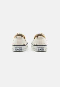 Płócienne trampki w kremowej bazie, z wielokolorowymi diamentowymi wzorami, żółtym akcentem wewnątrz oraz gumowymi podeszwami z logo.