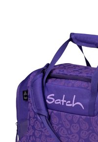 Purple duffel bag with floral pattern, adjustable straps, and top handle. Features a zipper closure and branding "Satch" in light purple.