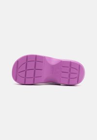 Suola di scarpa in gomma viola con motivo a battistrada, caratterizzata da una superficie liscia e scanalature definite per la trazione. Gli accenti includono il marchio del produttore.