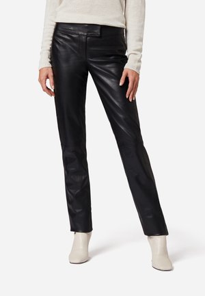Zwarte leren broek met een slim fit, met een zachte textuur en een platte tailleband. Gepaard met lichtgekleurde enkellaarsjes.
