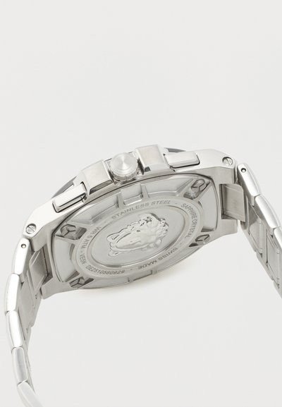 Ρολόι χειρός από ανοξείδωτο ατσάλι με μεταλλικό μπρασελέ, που διαθέτει χαραγμένο έμβλημα λιονταριού και κείμενο που υποδηλώνει κρύσταλλο ζαφείρι και κατασκευάστηκε στην Ελβετία στην πίσω θήκη.