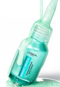 Bright Reveal Peeling Exfoliant de L'Oréal Paris, avec un flacon en verre teal arrondi, orné d'un motif texturé et d'un gel vert lisse qui s'égoutte.