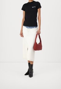 Svart åtsittande t-shirt med vitt logo, vit denim midi kjol, röd handväska och svarta spetsiga ankelstövlar. Släta texturer med minimalt mönster.