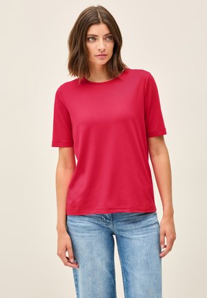 Red short-sleeve t-shirt made from smooth fabric. Round neckline and relaxed fit, paired with light blue wide-leg jeans.
