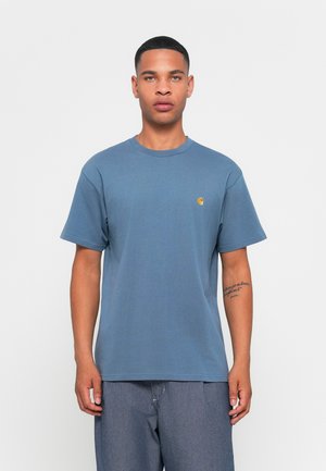 Blå bomulds T-shirt med korte ærmer og rund halsudskæring. Har et lille gult logo på venstre bryst. Enkel, afslappet pasform.