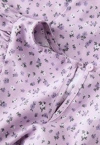 Tissu floral violet avec de petites fleurs blanches et vertes. Dispose d'une fermeture à bouton, d'une texture douce et d'un léger éclat.