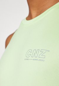 Világoszöld ujjatlan felső, textúrált anyagból, az elülső részen világosszürke "CNZ" logóval. Kerek nyakú, testhezálló dizájn.
