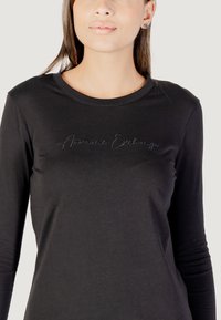 Schwarzes Langarm-T-Shirt aus weichem Stoff mit dezent gesticktem "Armani Exchange"-Logo auf der Vorderseite und rundem Halsausschnitt.