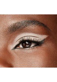 Close-up van een oog met een donkerbruine iris, dramatische zwarte eyeliner en lange wimpers. Lichtbeige oogschaduw contrasteert met de huidtint.
