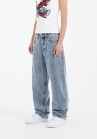 Light blue, loose-fitting denim jeans with a slightly faded texture, featuring traditional five-pocket design and belt loops.