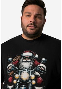 Černé tričko s podrobným grafickým vyobrazením Santa Clause na motorce, s brýlemi, červenou čepicí a taškou dárků.