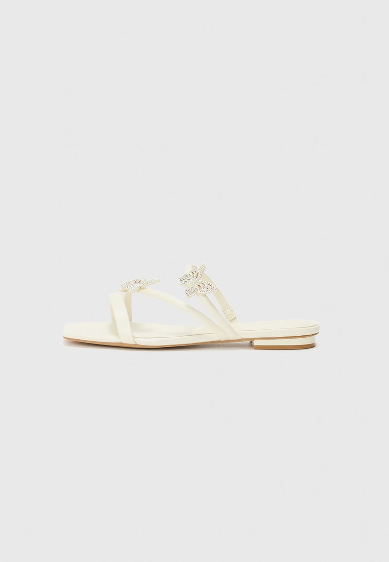 Light yellow sandals with butterfly embellishments and a flat sole, positioned on a plain white background.