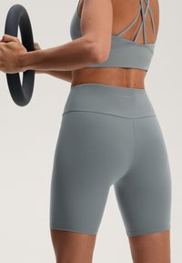 Ljusgråa träningsshorts och matchande crop top med korsettskaft. Slät textur och figursydd design. OYSHO-logotyp på midjebandet.