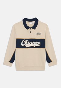 Camisa polo de manga larga beige con detalles en azul marino, que presenta los logotipos bordados de "Chicago" y "Diversidad", material de algodón y cuello.