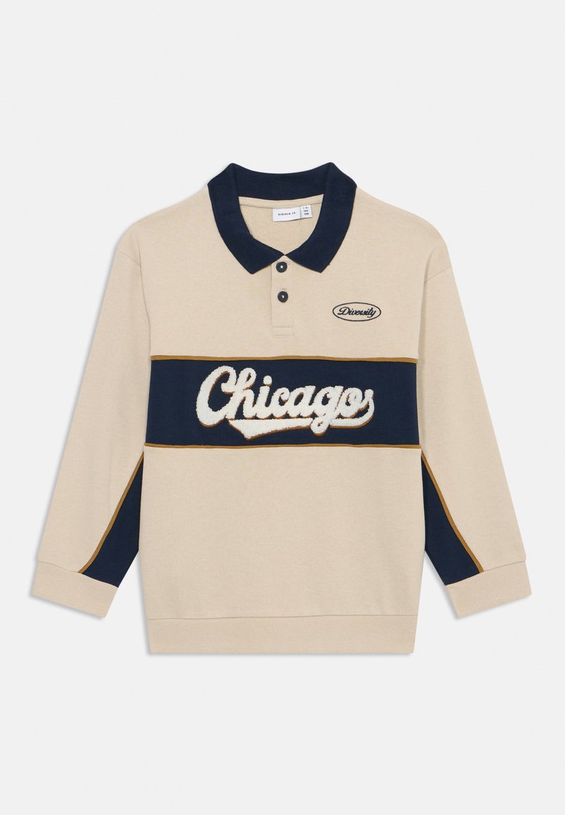 Camisa polo de manga larga beige con detalles en azul marino, que presenta los logotipos bordados de "Chicago" y "Diversidad", material de algodón y cuello.