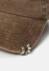 Brown corduroy cap featuring silver crescent moon and star embellishments on the brim, showcasing distinct stitching and texture details.