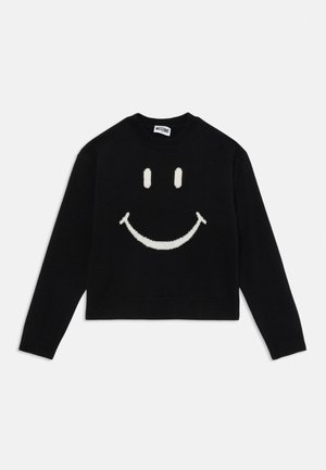 Svart genser med lange ermer og stort hvitt smiley-ansikt foran, samt en Moschino-label på innsiden av kragen.