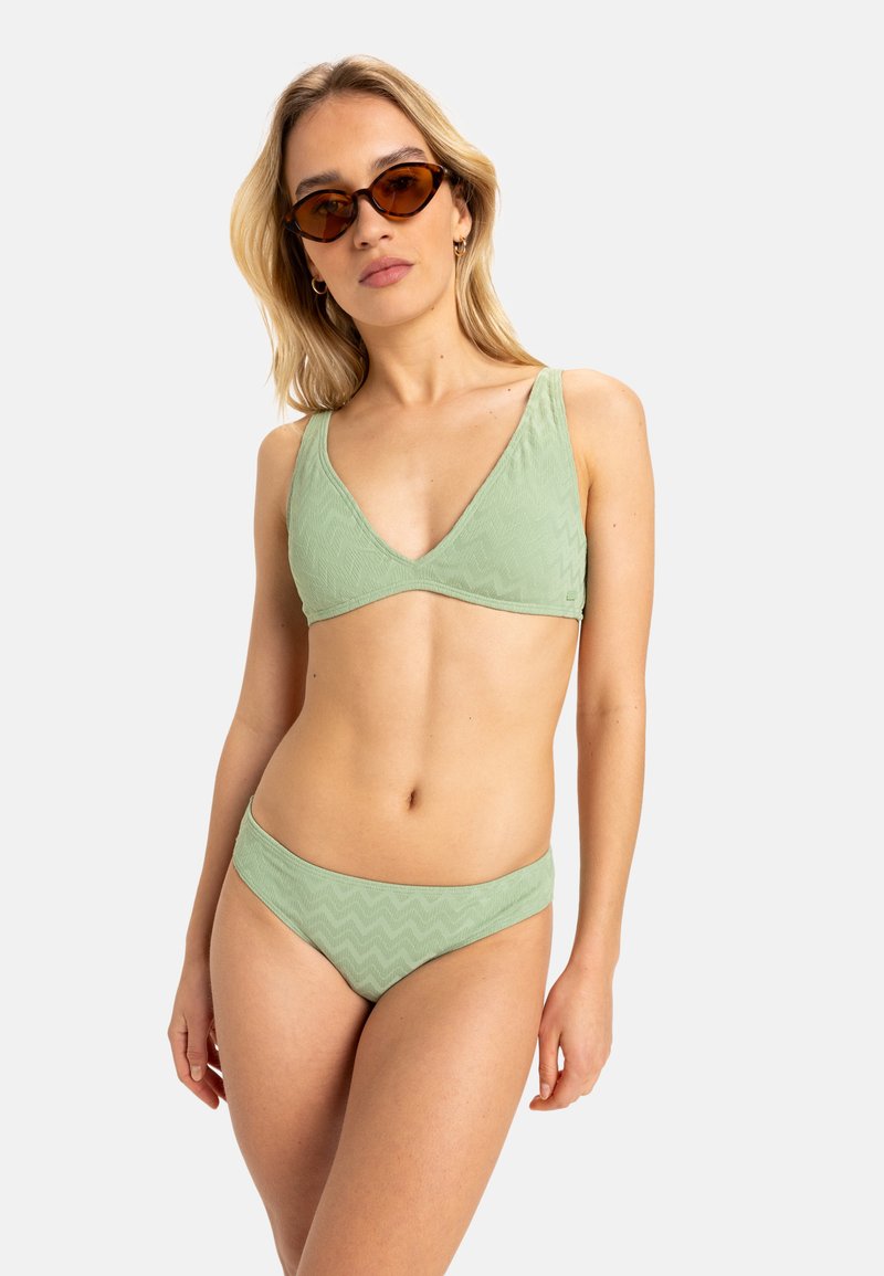 Ensemble de bikini à motifs zigzag verts avec un haut triangulaire et un bas taille basse, fabriqué en tissu texturé, accompagné de lunettes de soleil géométriques marron.