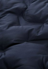 Posteljina u mornarsko plavoj boji glatke teksture, s kviltanim dizajnom i ispupčenim dijelovima koji stvaraju mekani izgled.