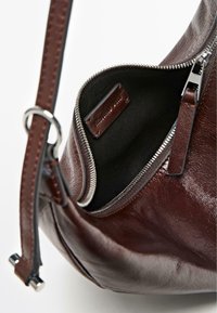 Bordeauxrote Lederhandtasche mit Reißverschluss und silberner Beschlägen, mit glatter Textur und kontrastierendem schwarzen Stofffutter.